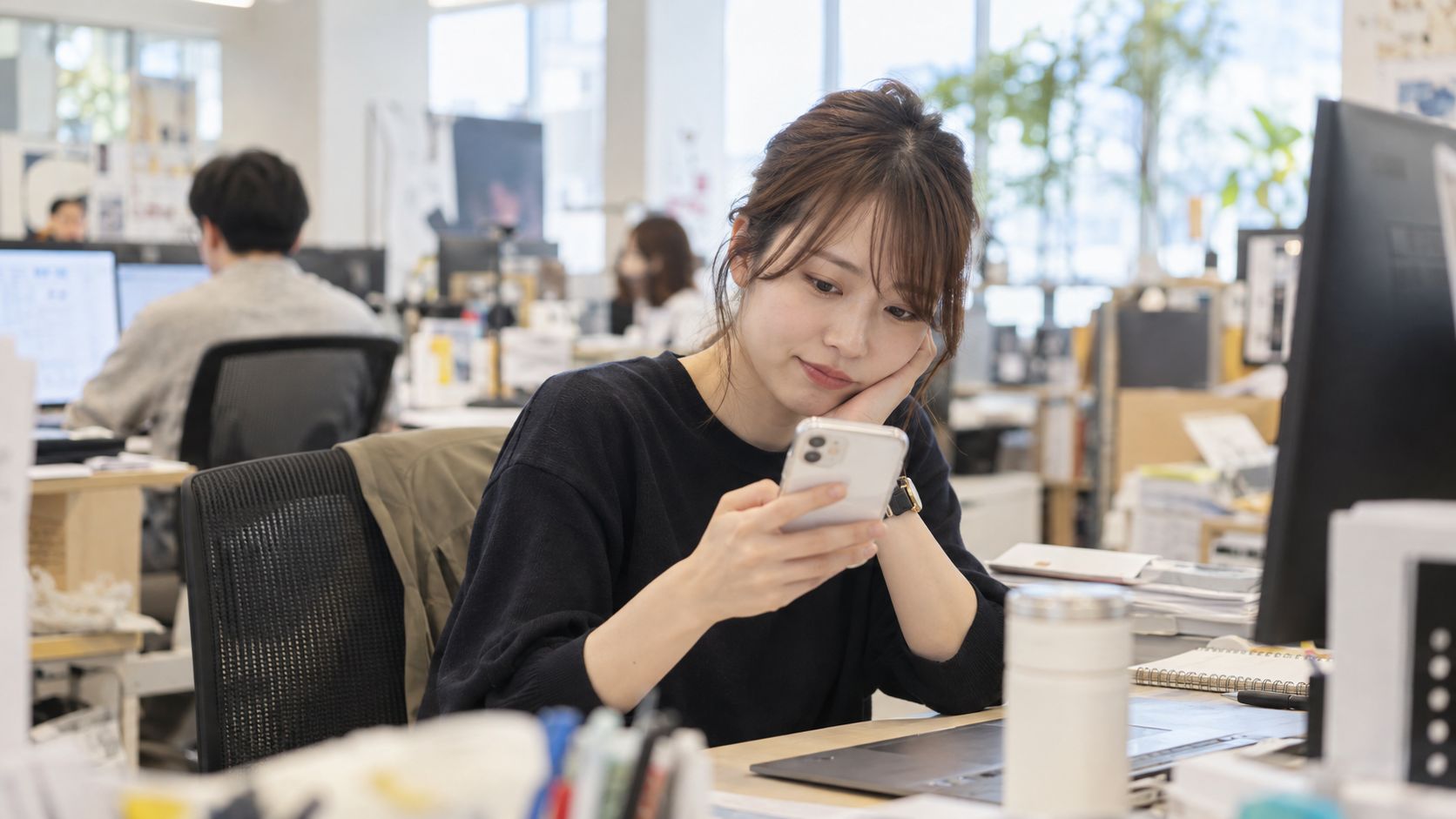 スマートフォンでSNSを確認する担当者